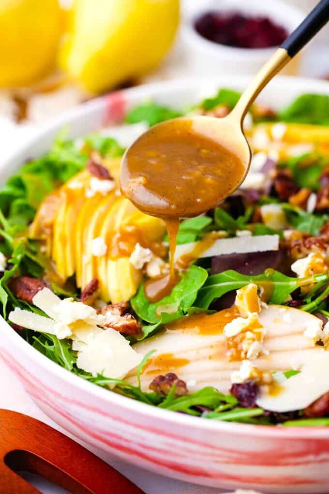 drizzling dressing with a soup on top of pear salad