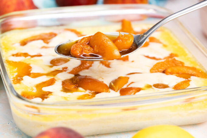 Scooping peach filling on top of cobbler base.