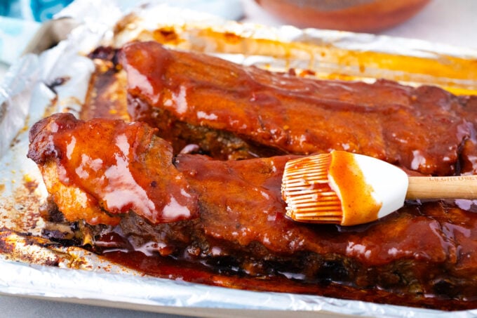 Brushing oven baked ribs with barbecue sauce.