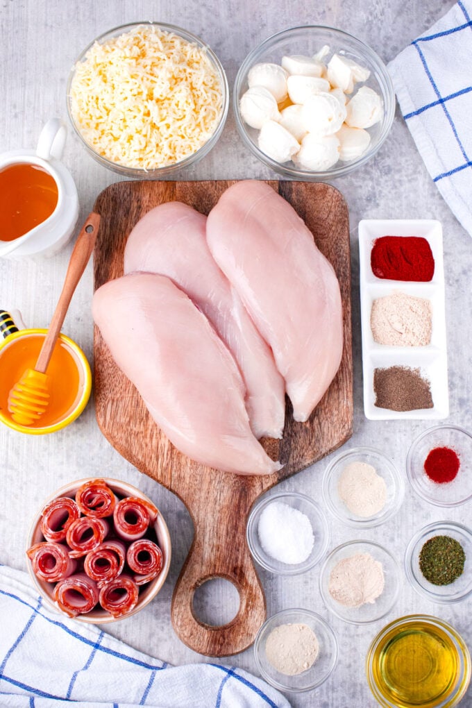 Overhead shot of bacon wrapped cream cheese stuffed chicken ingredients arranged on a table.