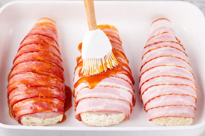 Brushing bacon wrapped cream cheese stuffed chicken with sweet and savory honey glaze.