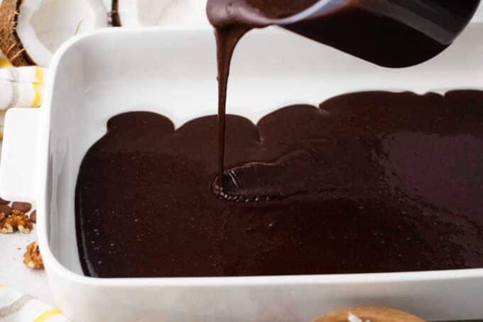 pouring chocolate cake batter into a baking pan