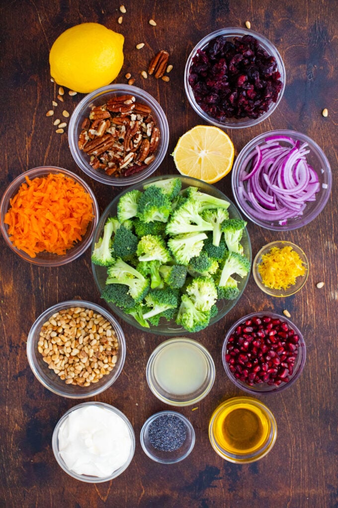 Overhead shot of broccoli salad ingredients in bowls on a wooden table.