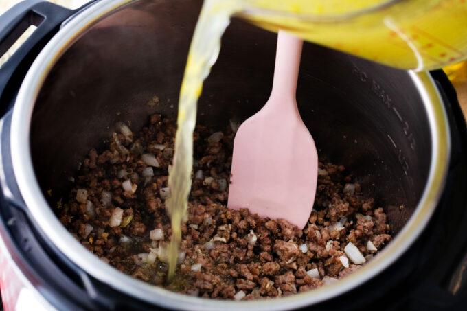 Adding broth to ground beef in the instant pot.