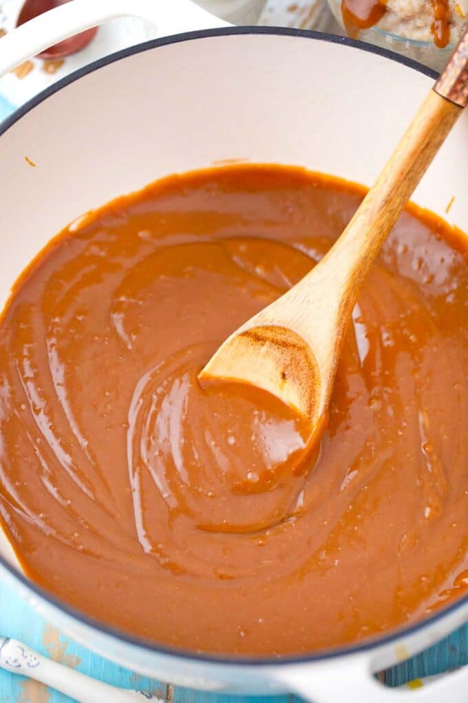 a sauce pan with caramel sauce and a wooden spoon dipped in it