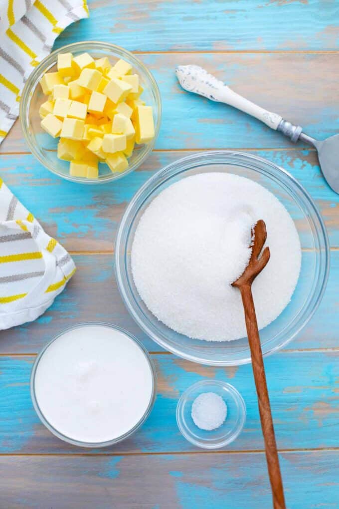 caramel sauce ingredients, sugar, butter, cream, salt, in bowls on a table