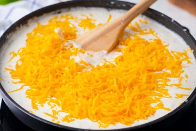 Making a cheesy sauce with lost of shredded cheese in a pan.