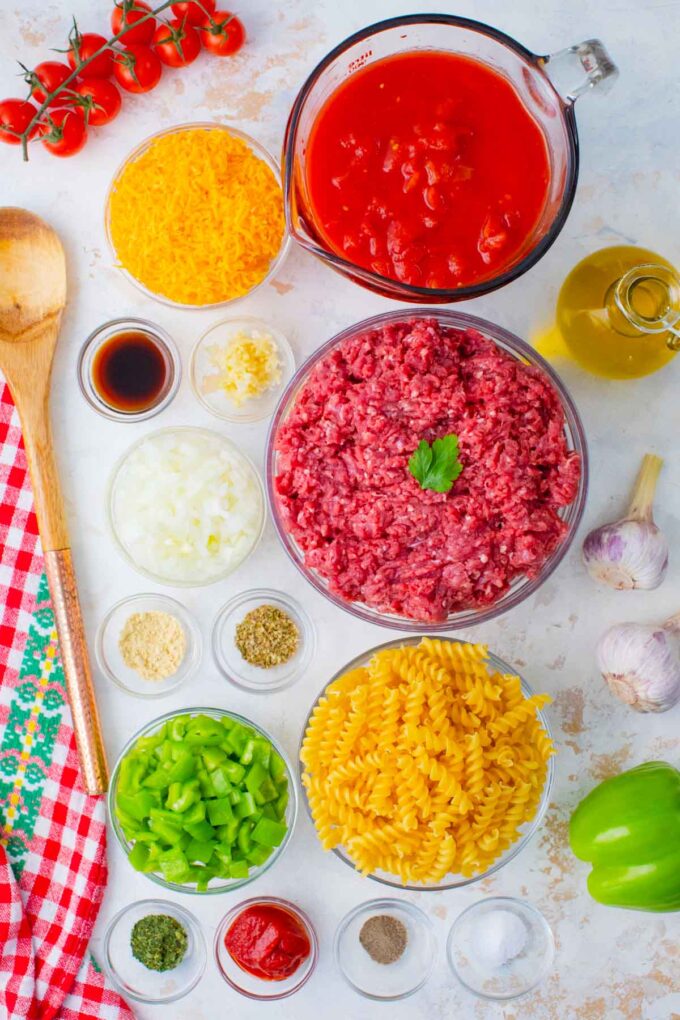 Overhead shot of cheeseburger casserole ingredients in bowls on a table.