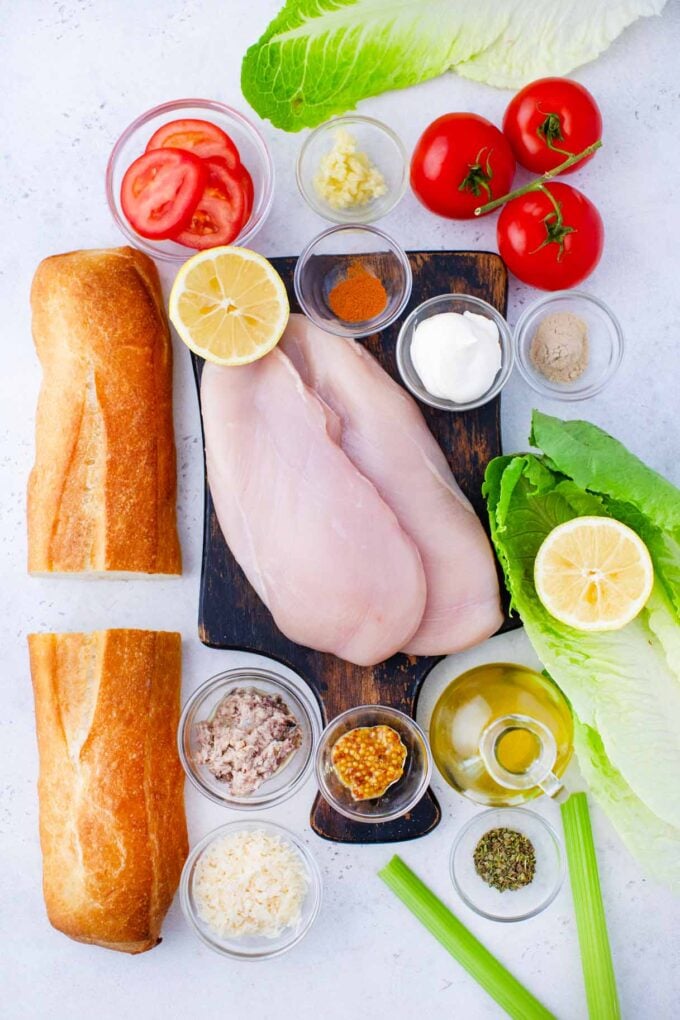 overhead shot of chicken caesar sandwiches ingredients arranged on a cutting board on a table