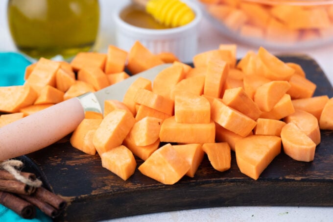 Chopping sweet potatoes on a cutting board.