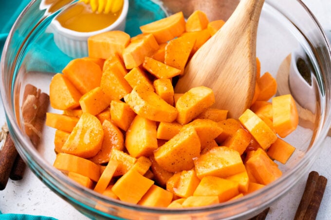 Mixing sweet potatoes pieces with brown sugar glaze.