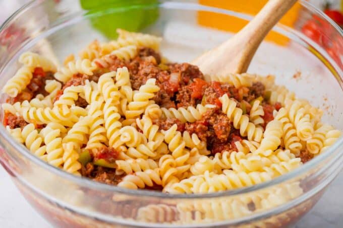 Combining cheeseburger casserole ingredients in a bowl.