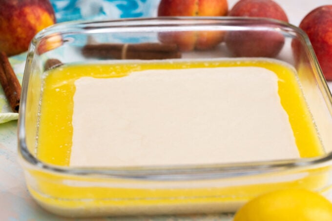 Melted butter and cobbler dough in a bking dish.