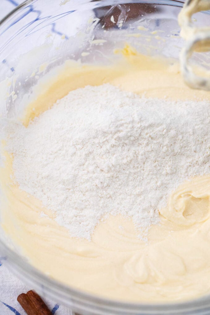 Adding flour to wet ingredients to make cinnamon cream cheese cookies.