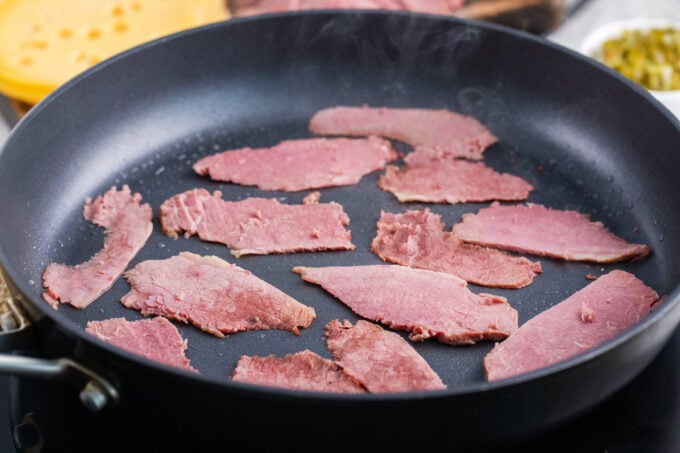 Reheating sliced corned beef in a skillet.