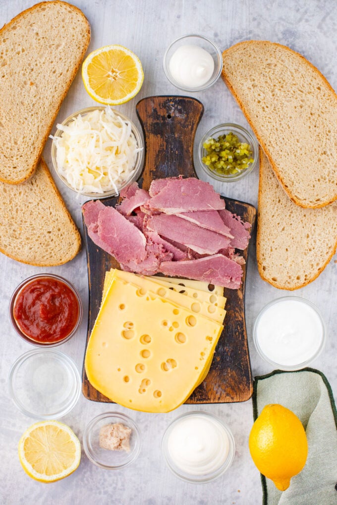 Overhead shot of corned beef sandwich ingredients on a white surface.