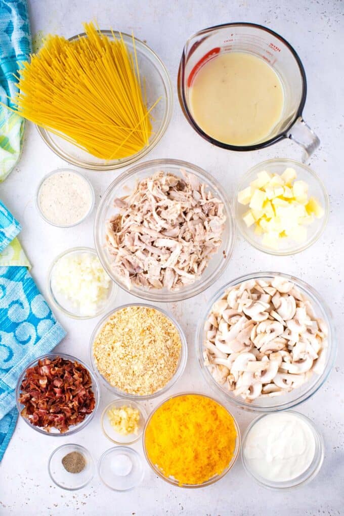 Overhead shot of crack chicken spaghetti casserole ingredients in bowls on a table.