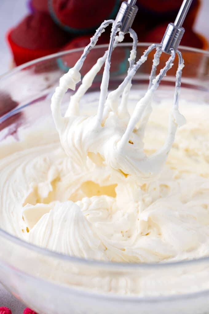 Beating cream cheese frosting with an electric hand mixer.