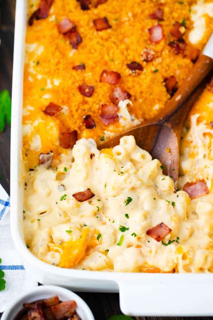 cheesy mac and cheese casserole in a baking dish, topped with cheddar cheese and crispy bacon