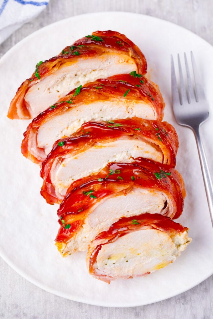 Sliced bacon wrapped cream cheese stuffed chicken.