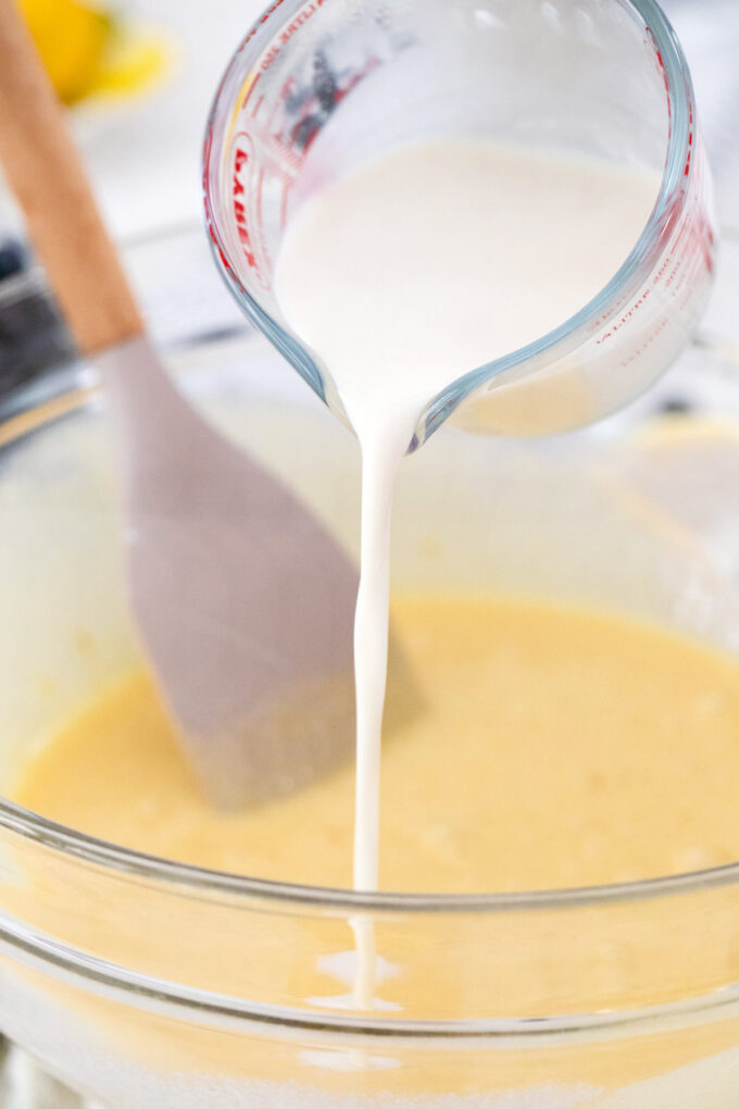 Whisking cream into beaten eggs to make custard.