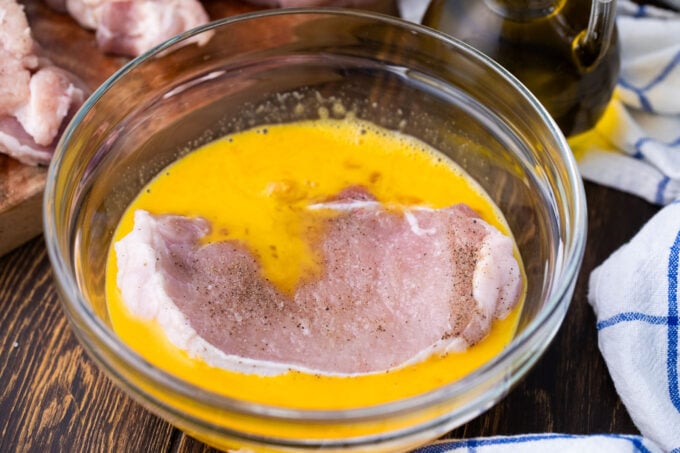 Dipping pork chop in beaten eggs.