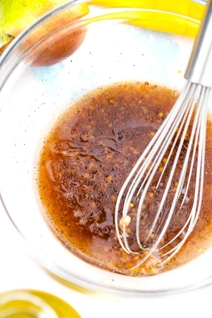 homemade honey mustard dressing in a bowl with a whisk