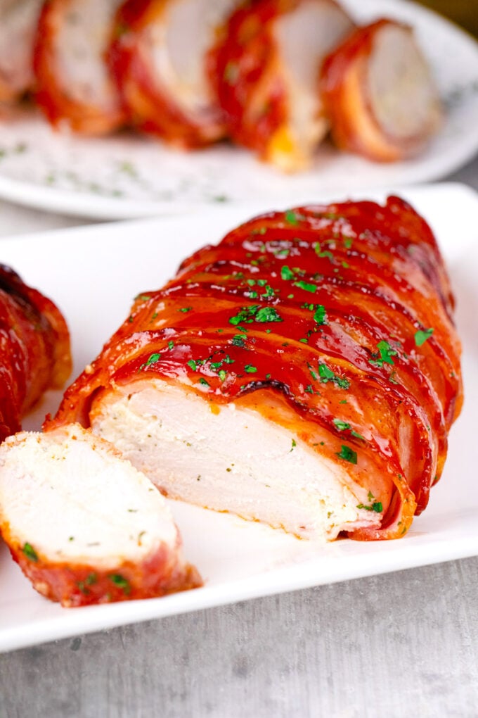 Bacon wrapped cream cheese stuffed chicken on a plate.