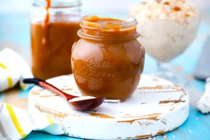 a jar of homemade 10 minute caramel sauce with rice pudding in the background