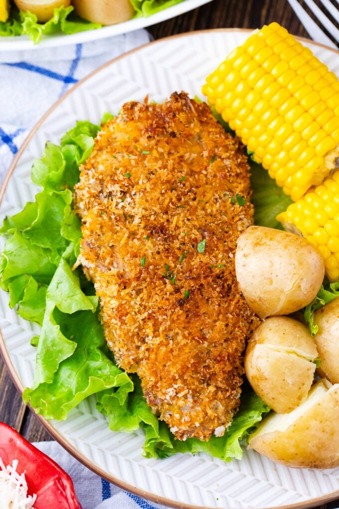Crispy baked pork chops with potatoes and corn on the cob.
