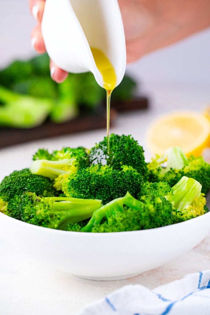 Drizzling olive oil over steamed broccoli.