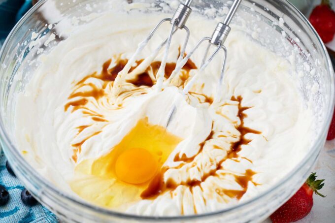 Mixing keto cheesecake filling ingredients in a bowl.