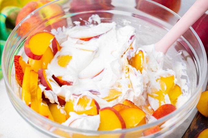 Folding sliced peaches into creamy cheesecake dressing.