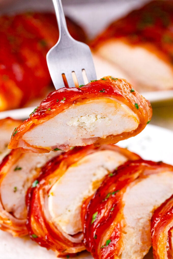 Sliced bacon wrapped cream cheese stuffed chicken.
