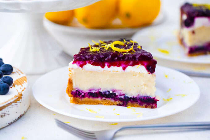 A slice of blueberry french custard cake with blueberry sauce and lemon zest.