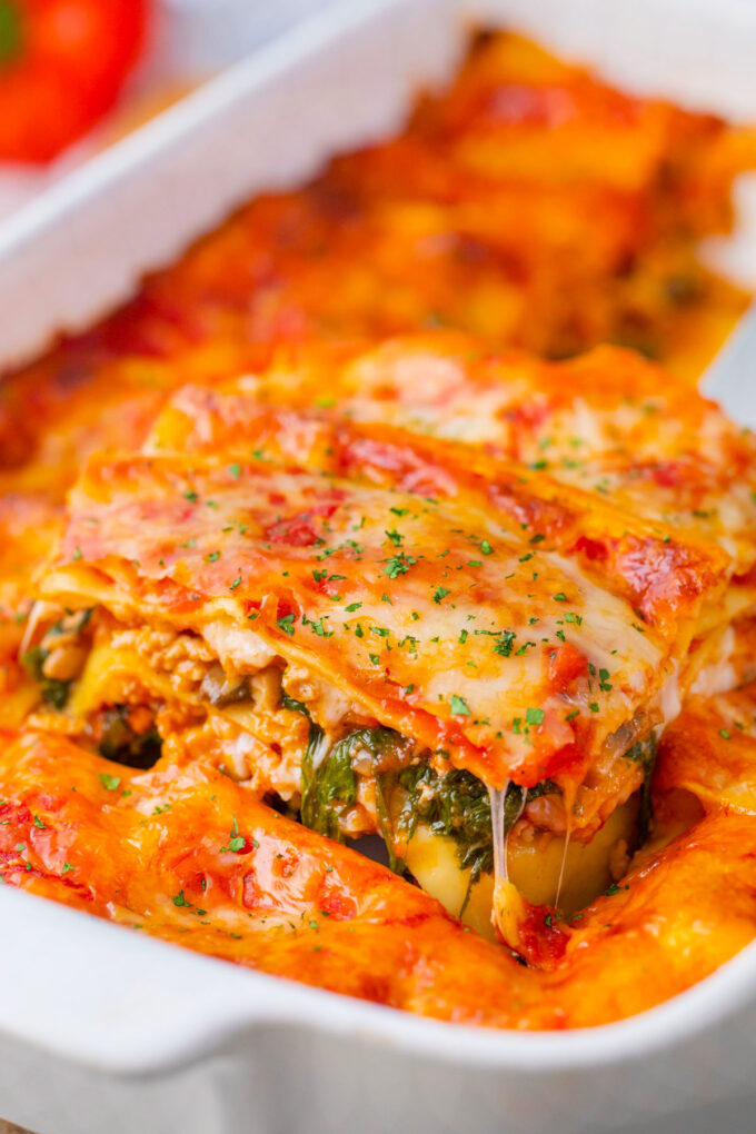 A slice of cheesy chicken spinach lasagna on a serving spatula.