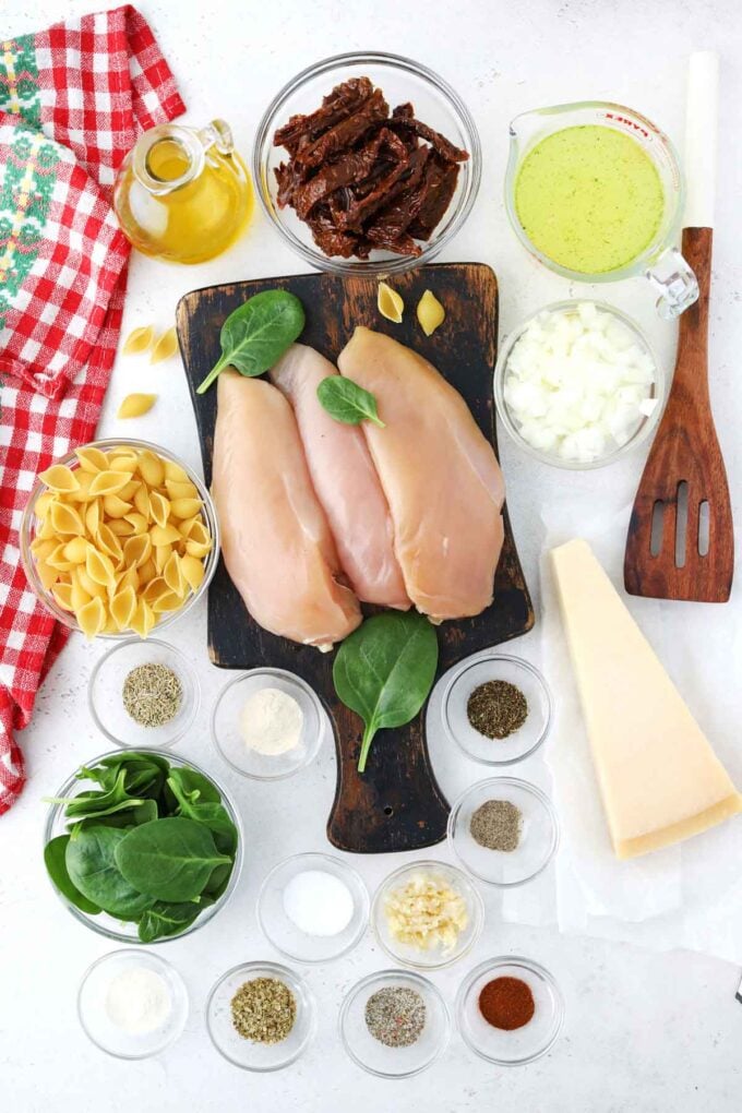 instant pot tuscan chicken pasta ingredients arranged in bowls on a white surface