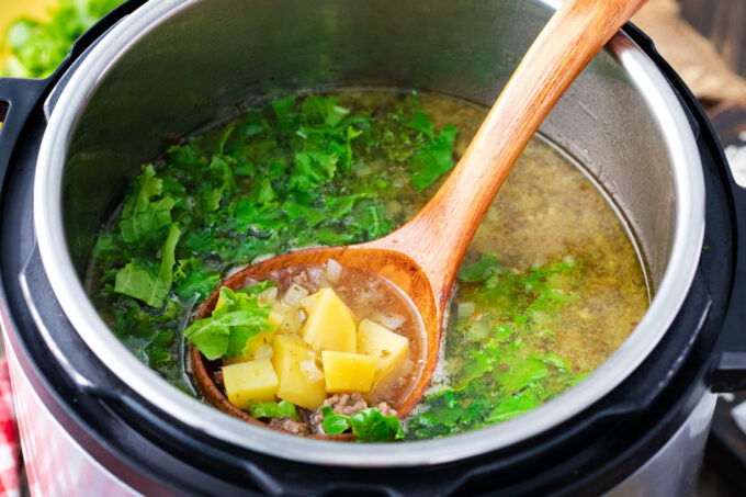 Adding kale to zuppa toscana in the instant pot.