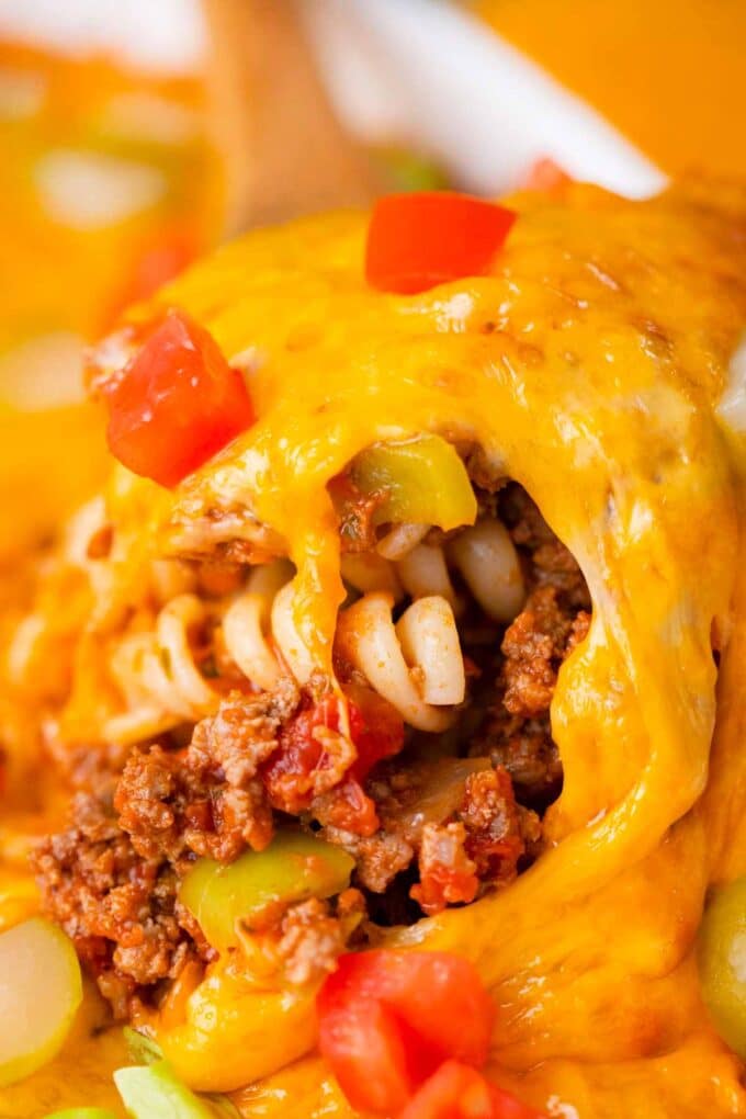 A serving spoon of very cheesy cheeseburger casserole.