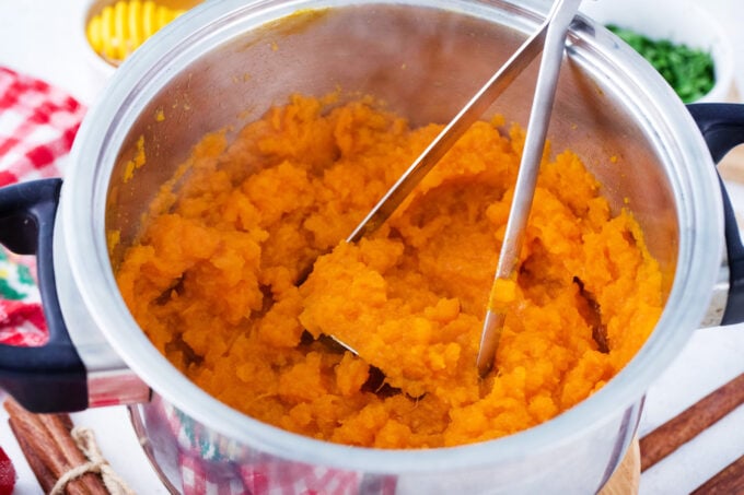 Mashing sweet potatoes in a pot.