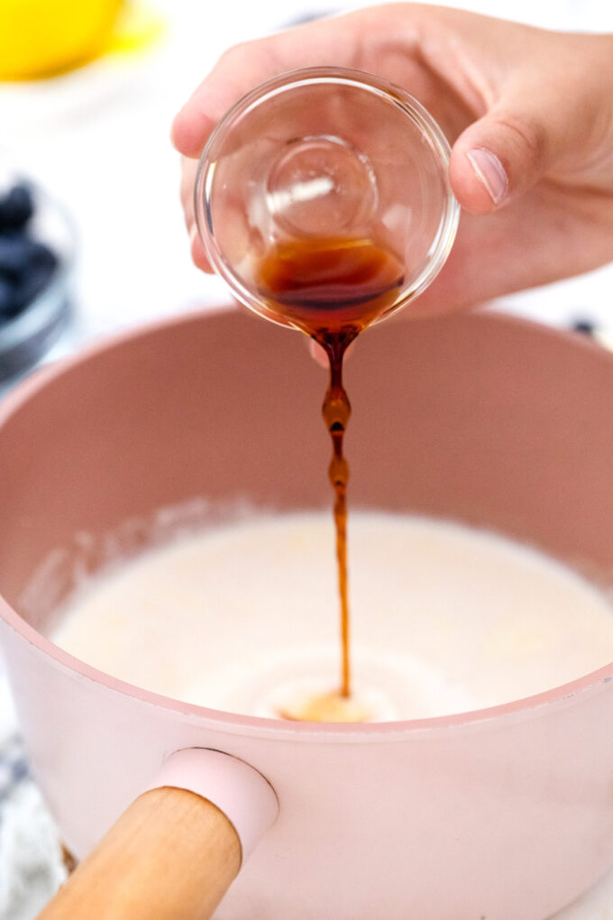 Adding vanilla extract to creamy custard in a saucepan.