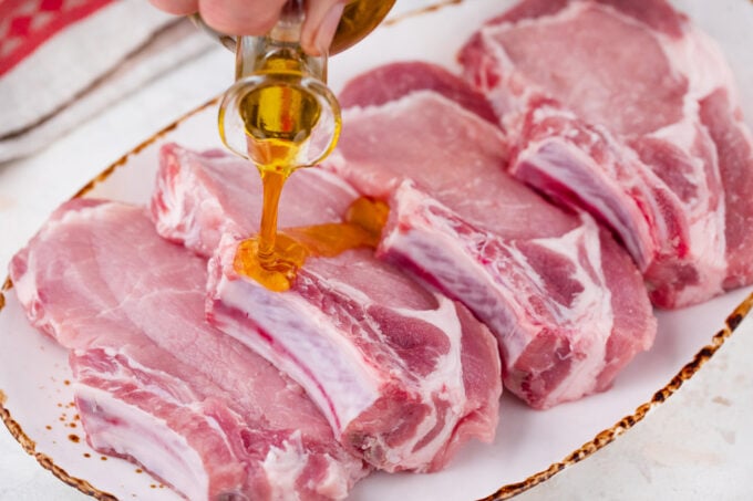 Rubbing pork chops with olive oil.