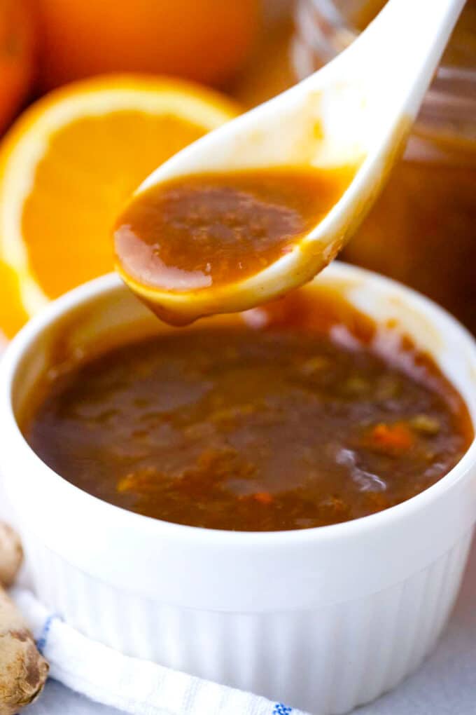 orange sauce dripping of a spoon in a ramekin