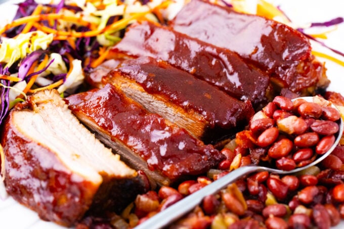 Oven baked barbecue ribs with coleslaw and baked beans.