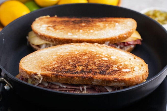 Cooking homemade Reuben sandwiches in a skillet.