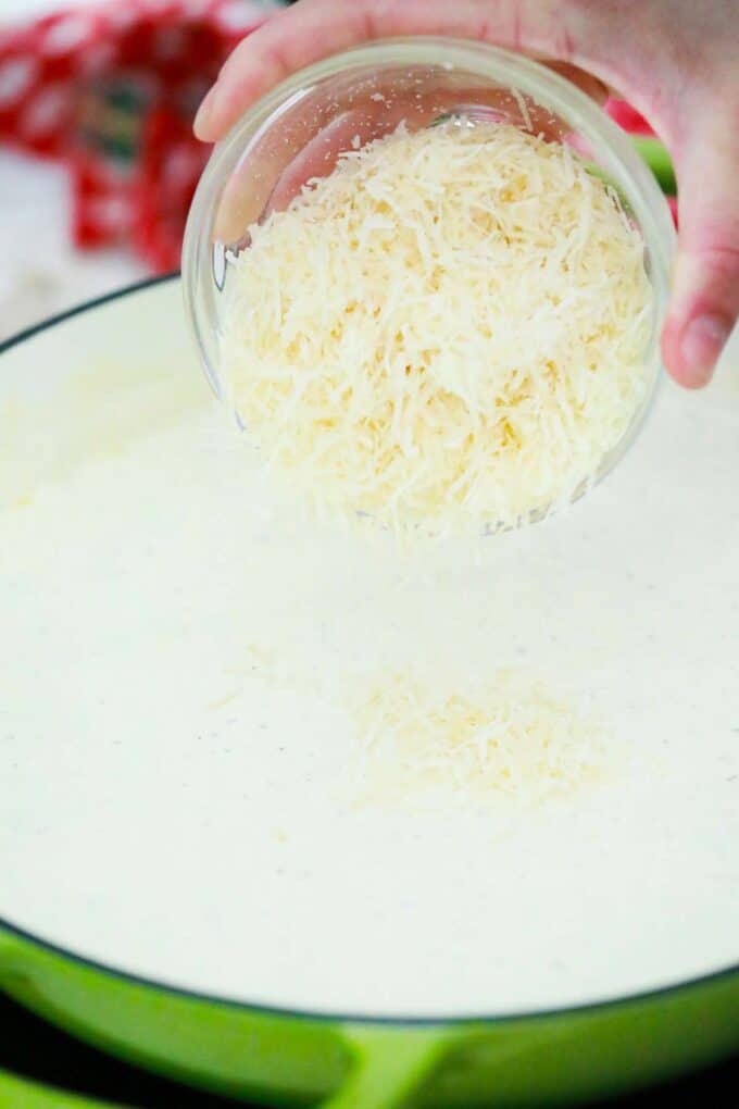 adding parmesan cheese to homemade Alfredo sauce