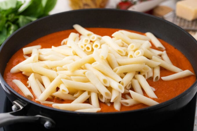Adding pasta to vodka sauce.