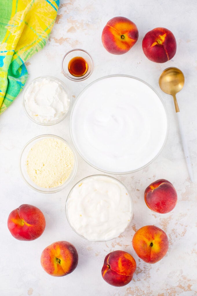 Overhead shot of peach cheesecake salad ingredients in bowls on a table.