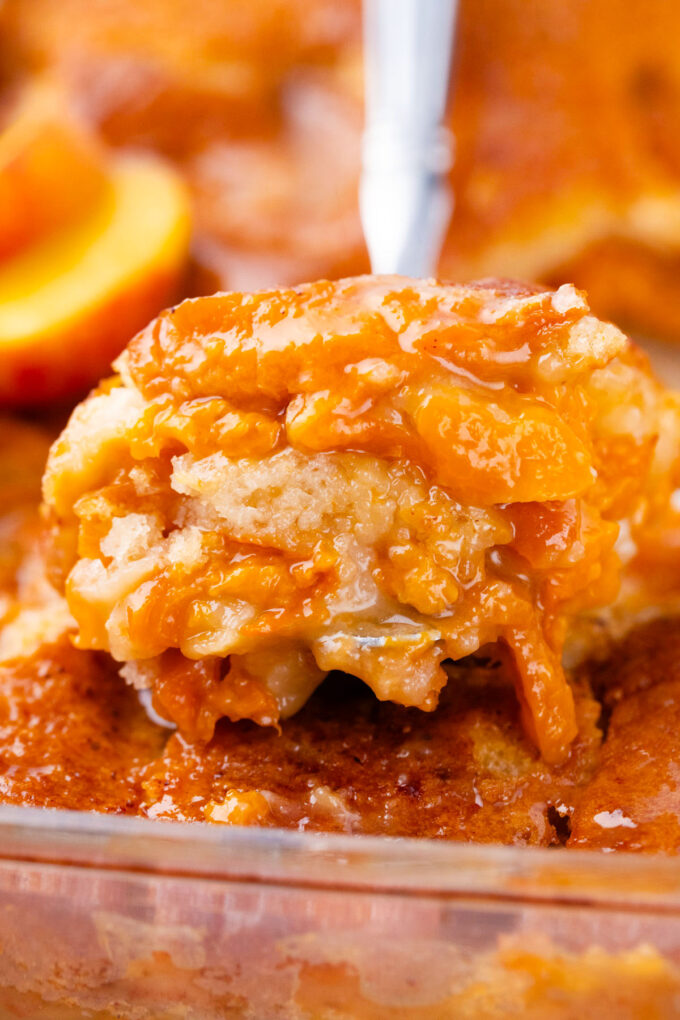 Close shot of a serving spoon of homemade peach cobbler.