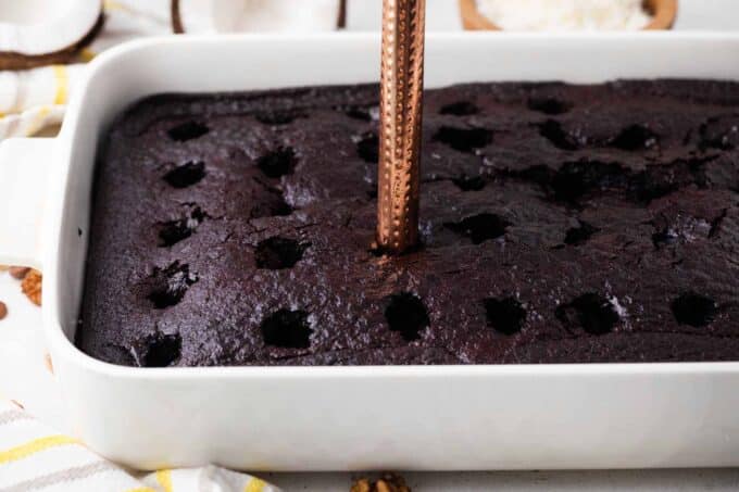 poking holes with a wooden spoon in a chocolate cake